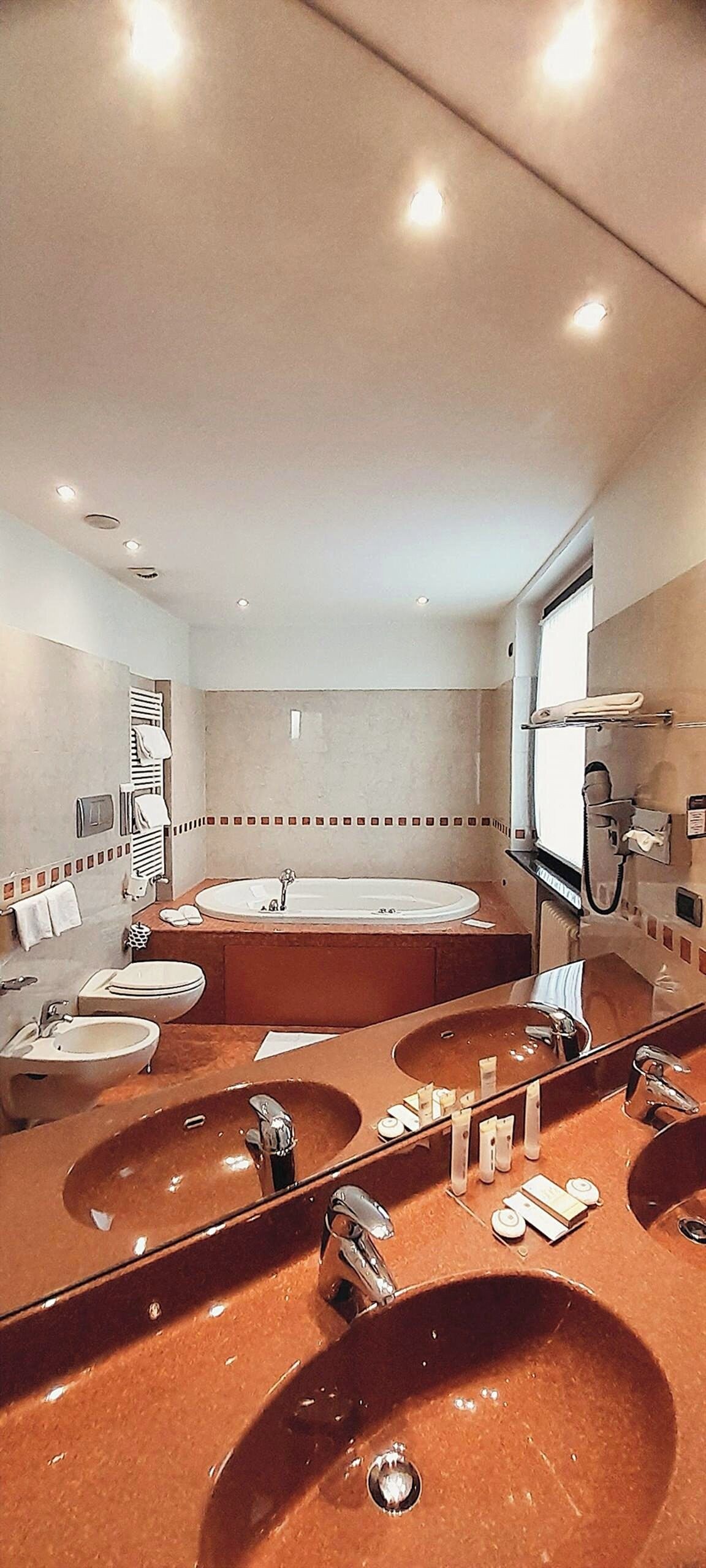 A bathroom with two sinks, a bathtub, and a large mirror.