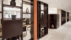 Un interior moderno con una zona de cocina, una mesa de comedor y un pasillo con estanterías.
