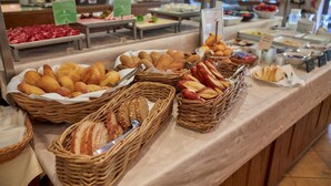 Een buffet met diverse gerechten, zoals brood, gebak en fruit.