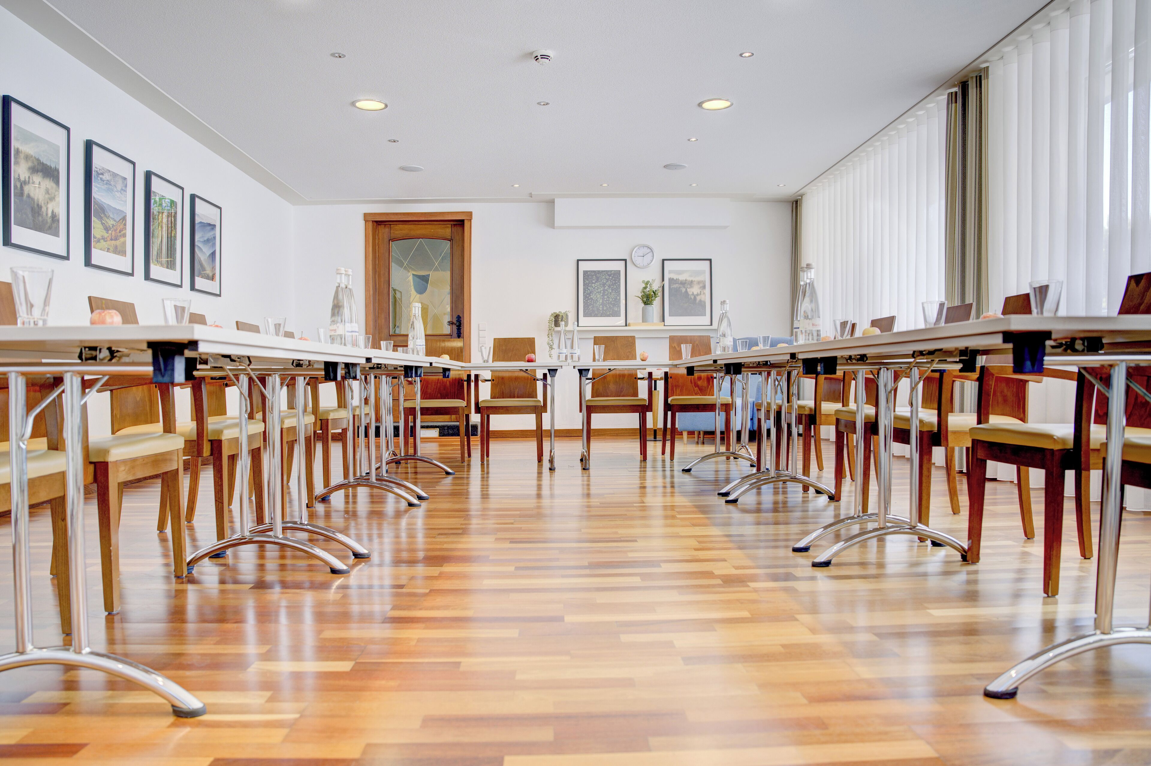 Uma sala de conferência com uma mesa comprida, cadeiras e piso de madeira.