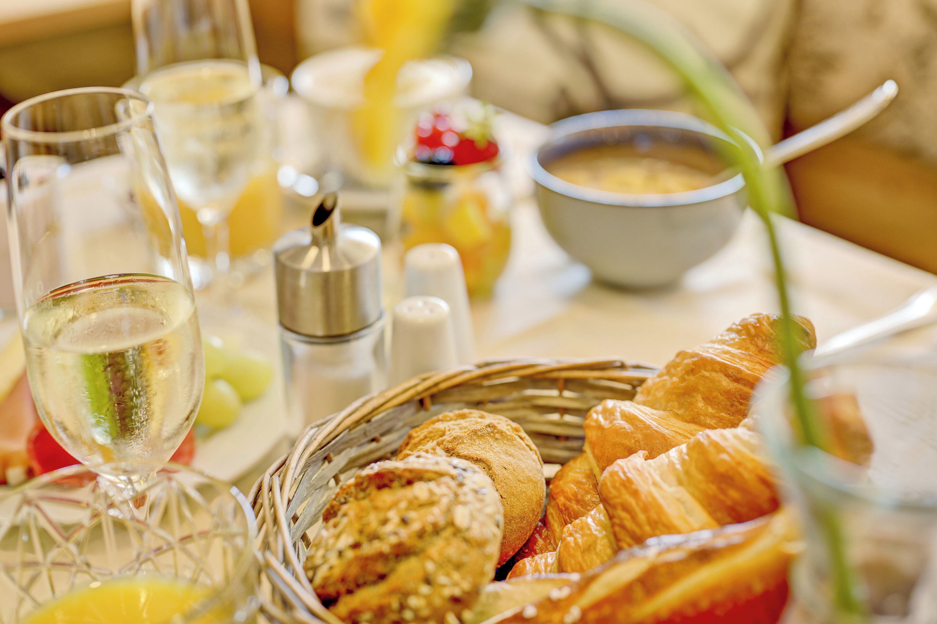 A breakfast setting with croissants, orange juice, and a bowl of soup.