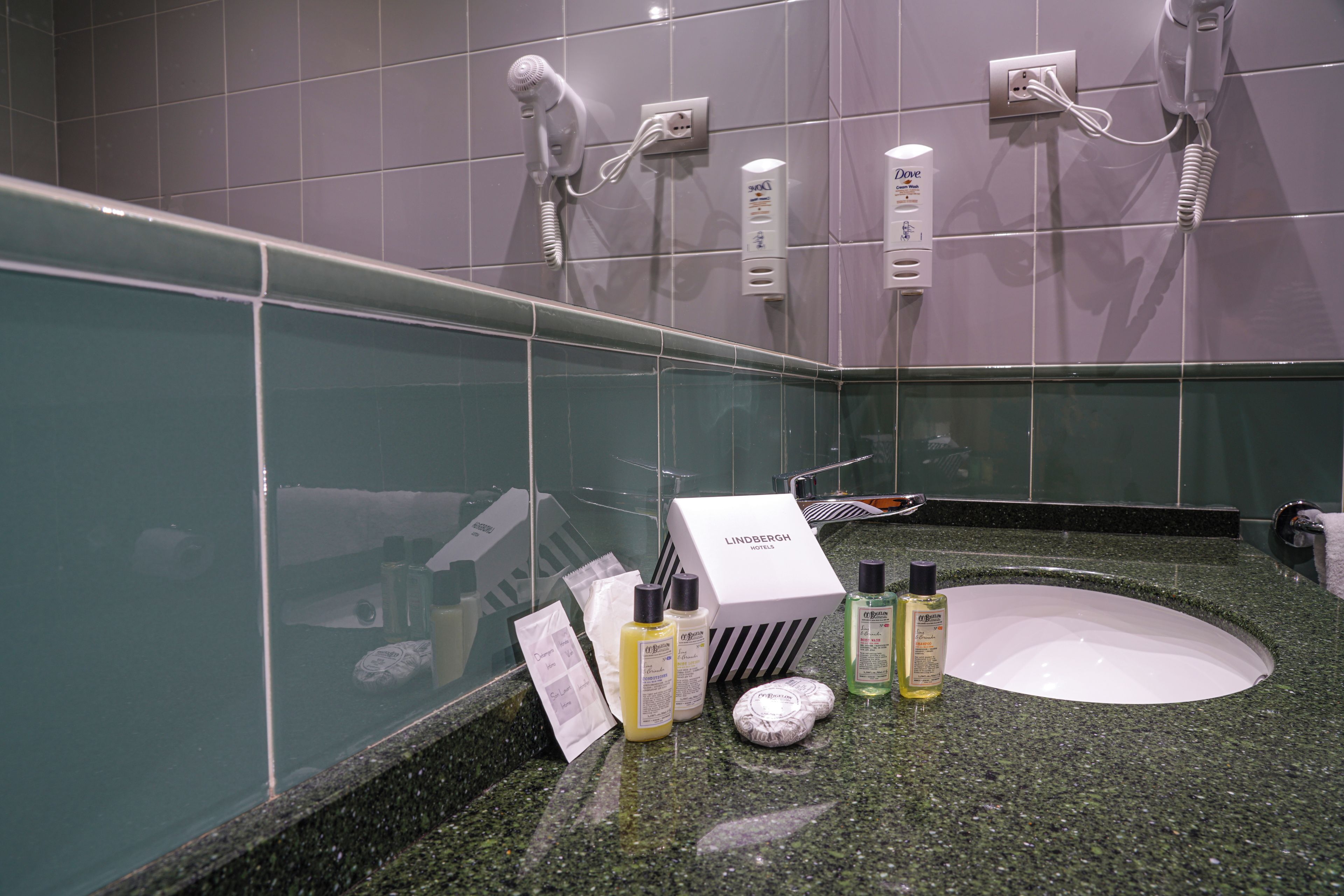 A bathroom with a granite countertop, a white sink, and toiletries including a bottle of lotion and a box of soap.