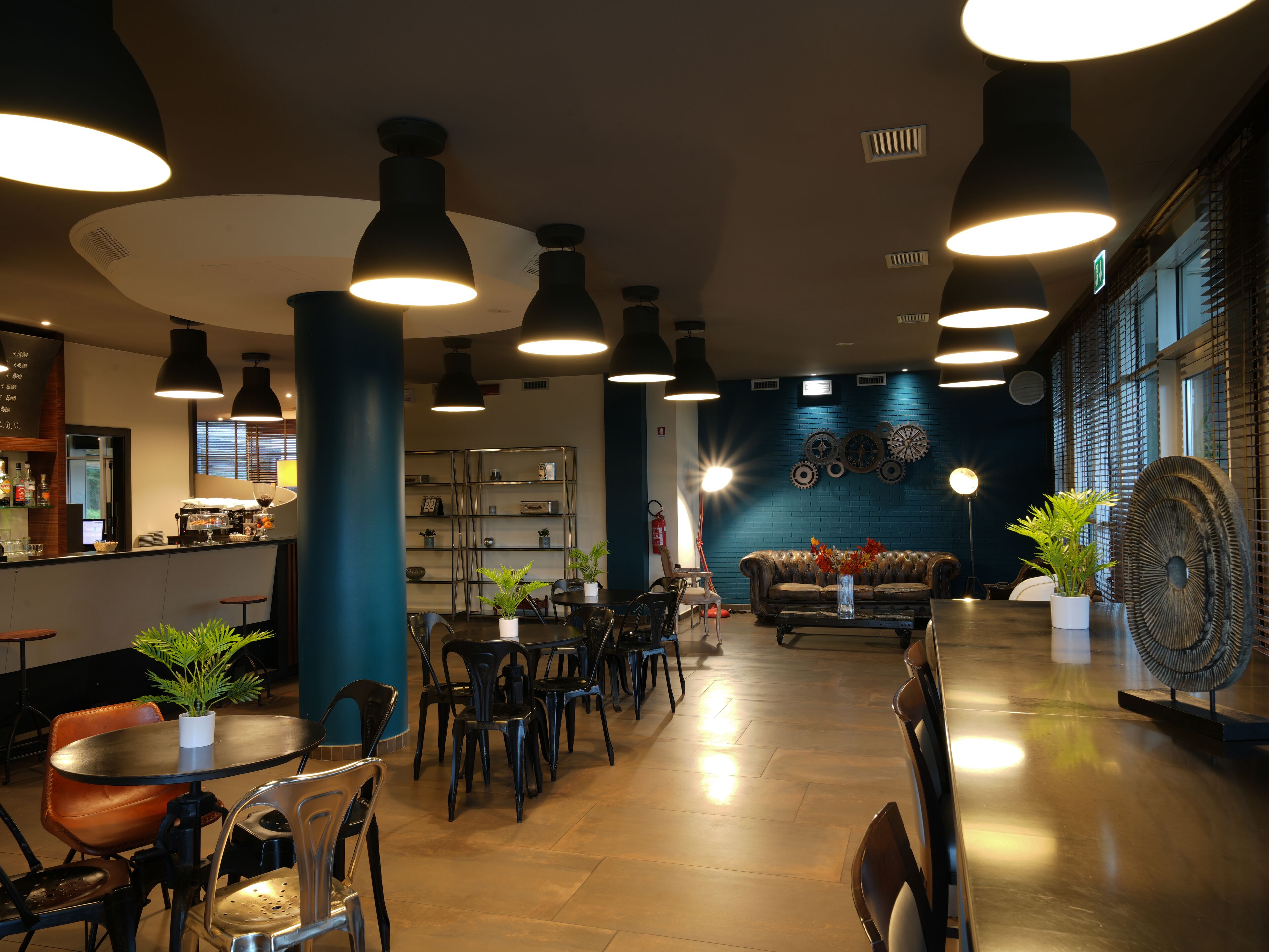 A modern cafe interior with multiple seating areas, including tables and chairs, and a bar counter.