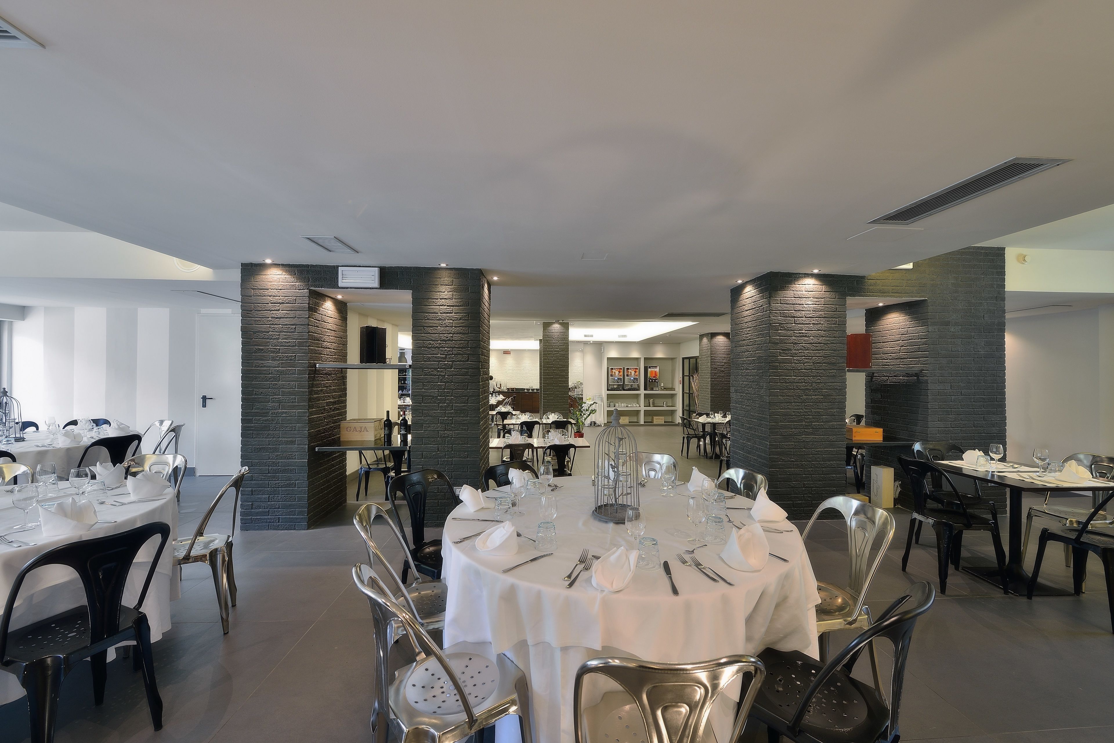 Un comedor amplio con mesas redondas dispuestas para varios comensales, con sillas modernas y un elemento decorativo central.