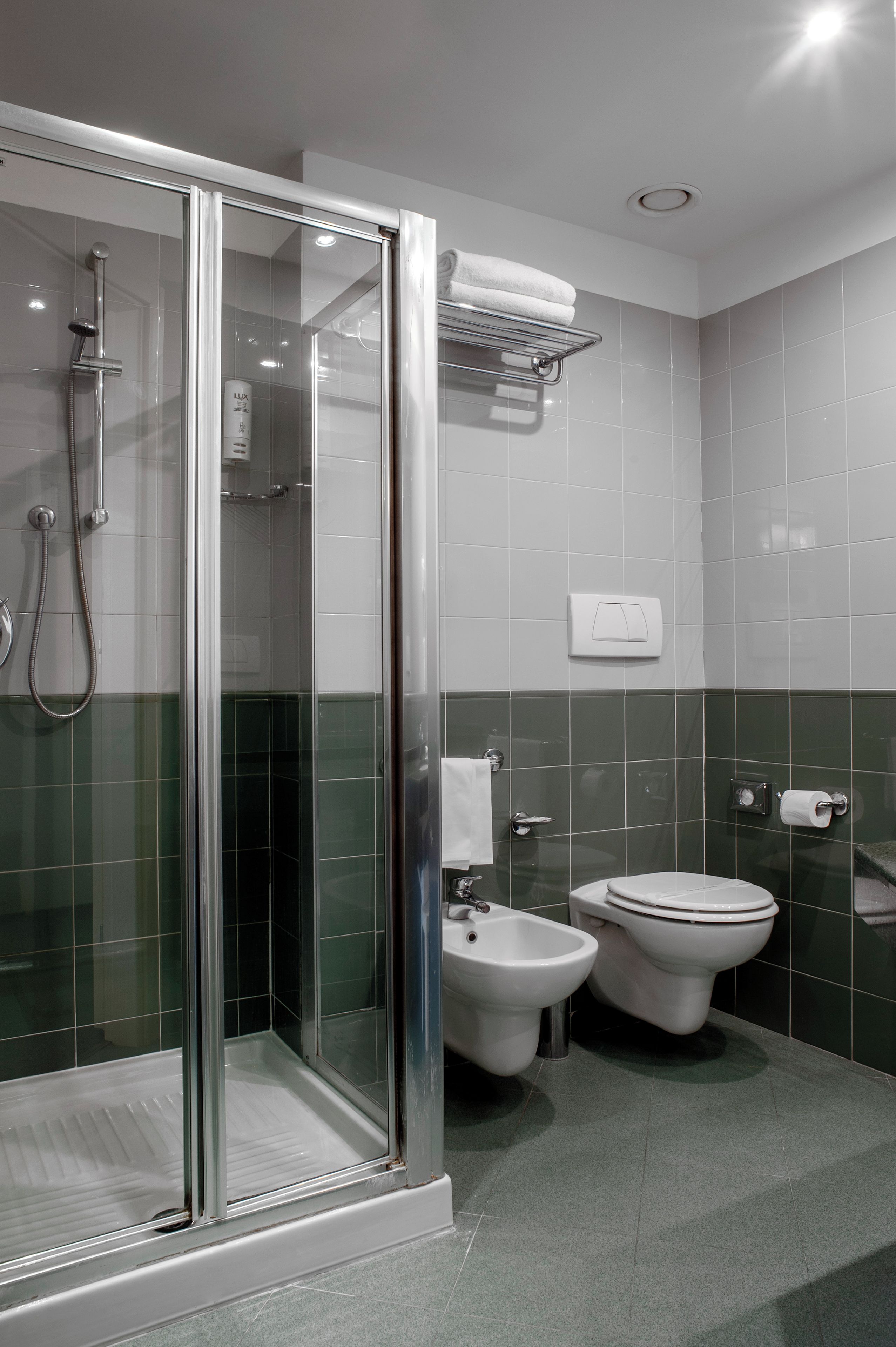 Une salle de bain moderne avec une douche à parois de verre, un bidet, des toilettes et un porte-serviettes.