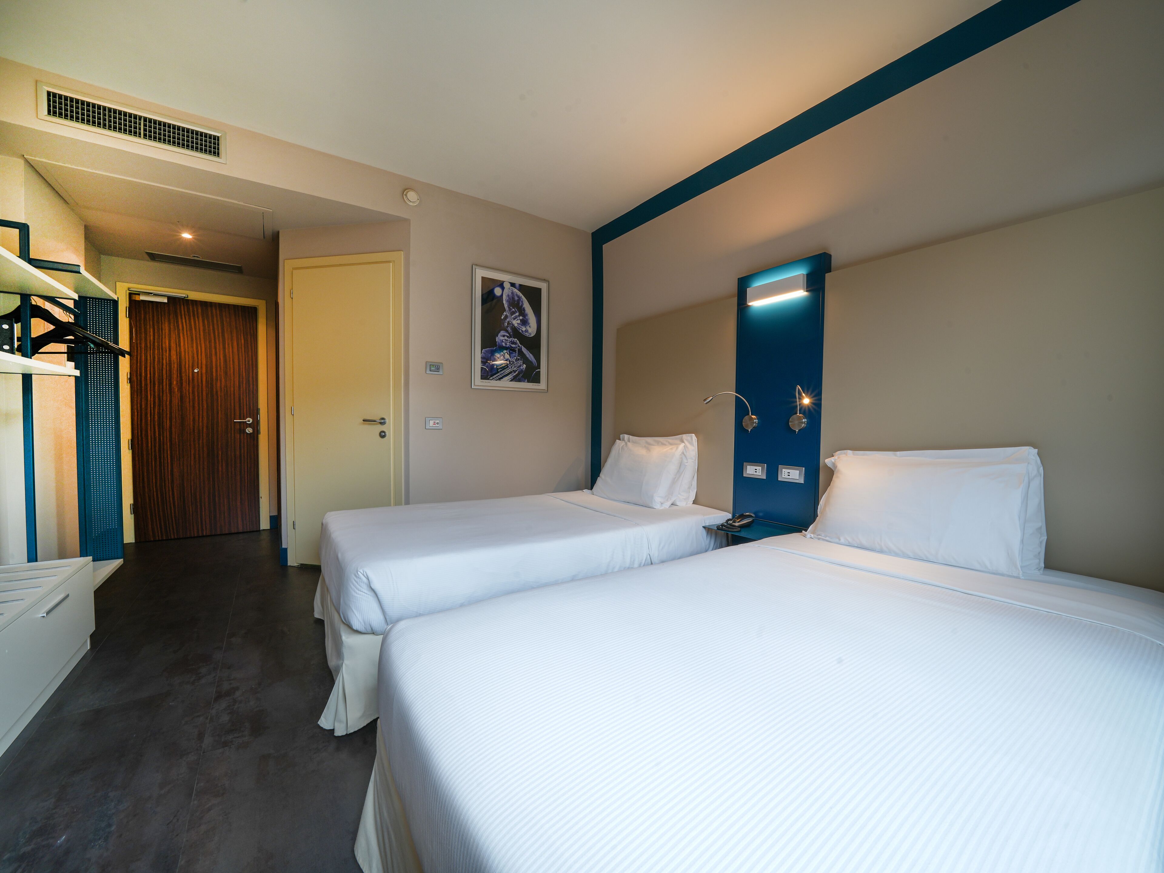 Een hotelkamer met twee eenpersoonsbedden, een badkamer en een trap naar een verdieping hoger.