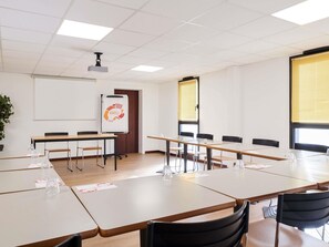 A conference room with tables, chairs, a projector, a whiteboard, and a plant. - Aparthotel Adagio Access Rennes Centre (Rennes)
