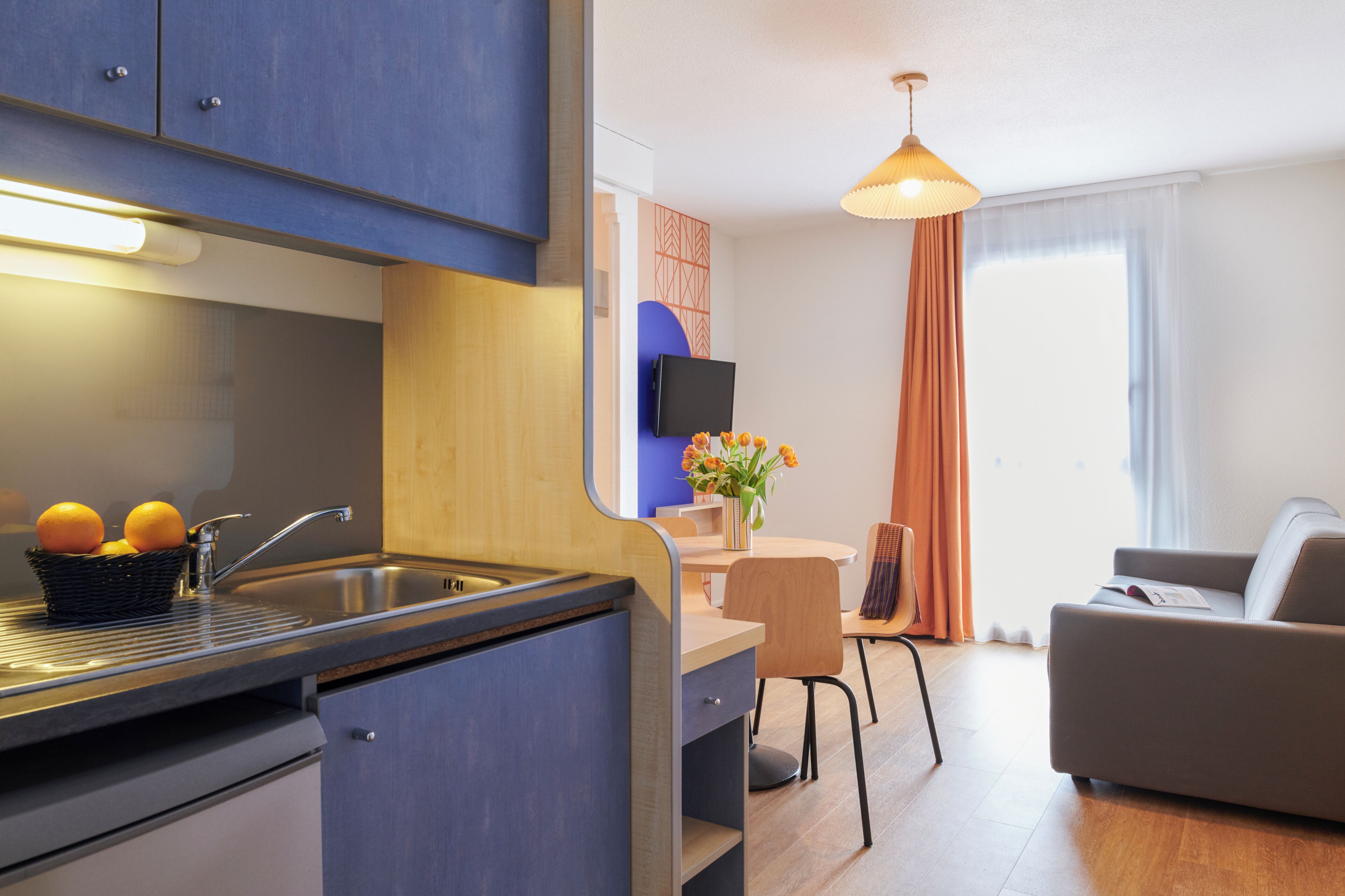 Een moderne keuken met een spoelbak, een eetgedeelte met een tafel en stoelen, en een woonkamer met een bank.