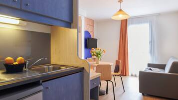 Een moderne keuken met een spoelbak, een eetgedeelte met een tafel en stoelen, en een woonkamer met een bank.