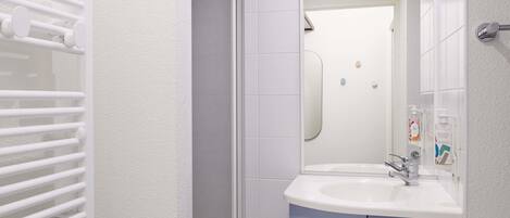 A bathroom with a white sink, blue cabinets, a glass shower enclosure, and a white towel rack.