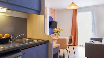 Una cocina moderna con un lavamanos, un comedor con mesa y sillas, y una sala de estar con sofá.