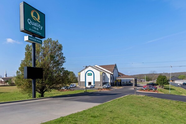 A Quality Inn by Choice Hotels with an indoor pool, a church in the background, and a clear sky.