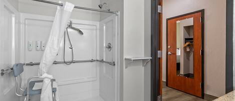 Douche toegankelijk voor rolstoelen, met glazen deur, handgreep en handdoekhouder.