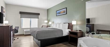 A hotel room with a bed, a desk, a chair, a TV, a bathroom with a bathtub, and a window.