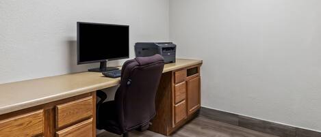 A workspace with a desk, computer, printer, and office chair.