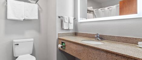 A bathroom with a toilet, sink, mirror, towel rack, and a shower curtain.