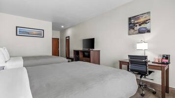 A hotel room with two beds, a desk with a chair, a television, and artwork on the walls.