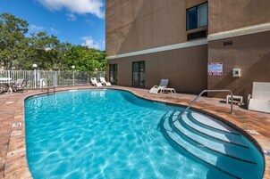 Una piscina con zona de solárium, sillas de descanso y un cartel de 'No Diving'.