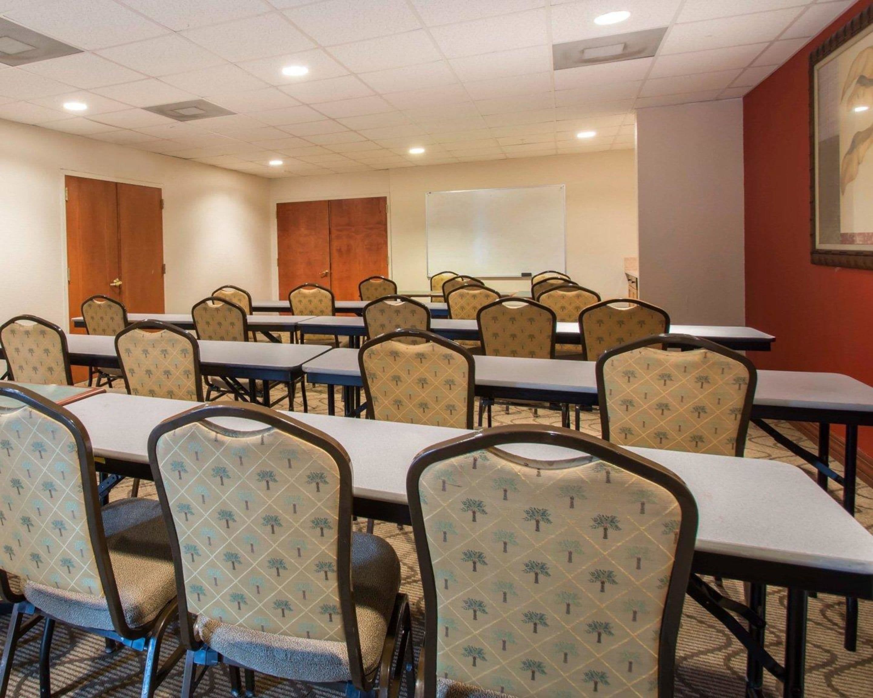 A conference room with tables and chairs, a whiteboard, and a door.