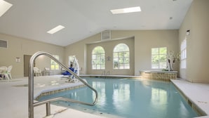 An indoor swimming pool with clear water, a metal ladder, and a bench.