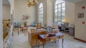 A spacious room with a high ceiling, a large fan, a desk with a computer, and a bicycle mounted on the wall.