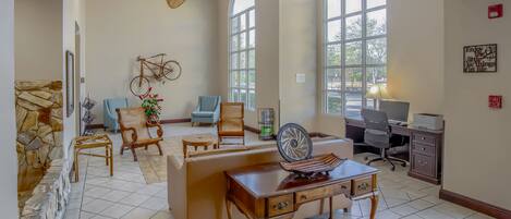 A spacious room with a high ceiling, a large fan, a desk with a computer, and a bicycle mounted on the wall.