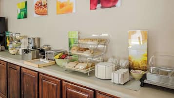 Een ontbijtbuffet met diverse gerechten, een koffieapparaat en een schaal fruit.