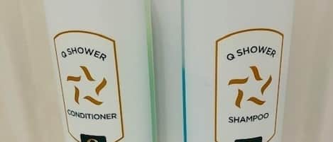 Two bottles of Q Shower conditioner and shampoo in a bathroom.
