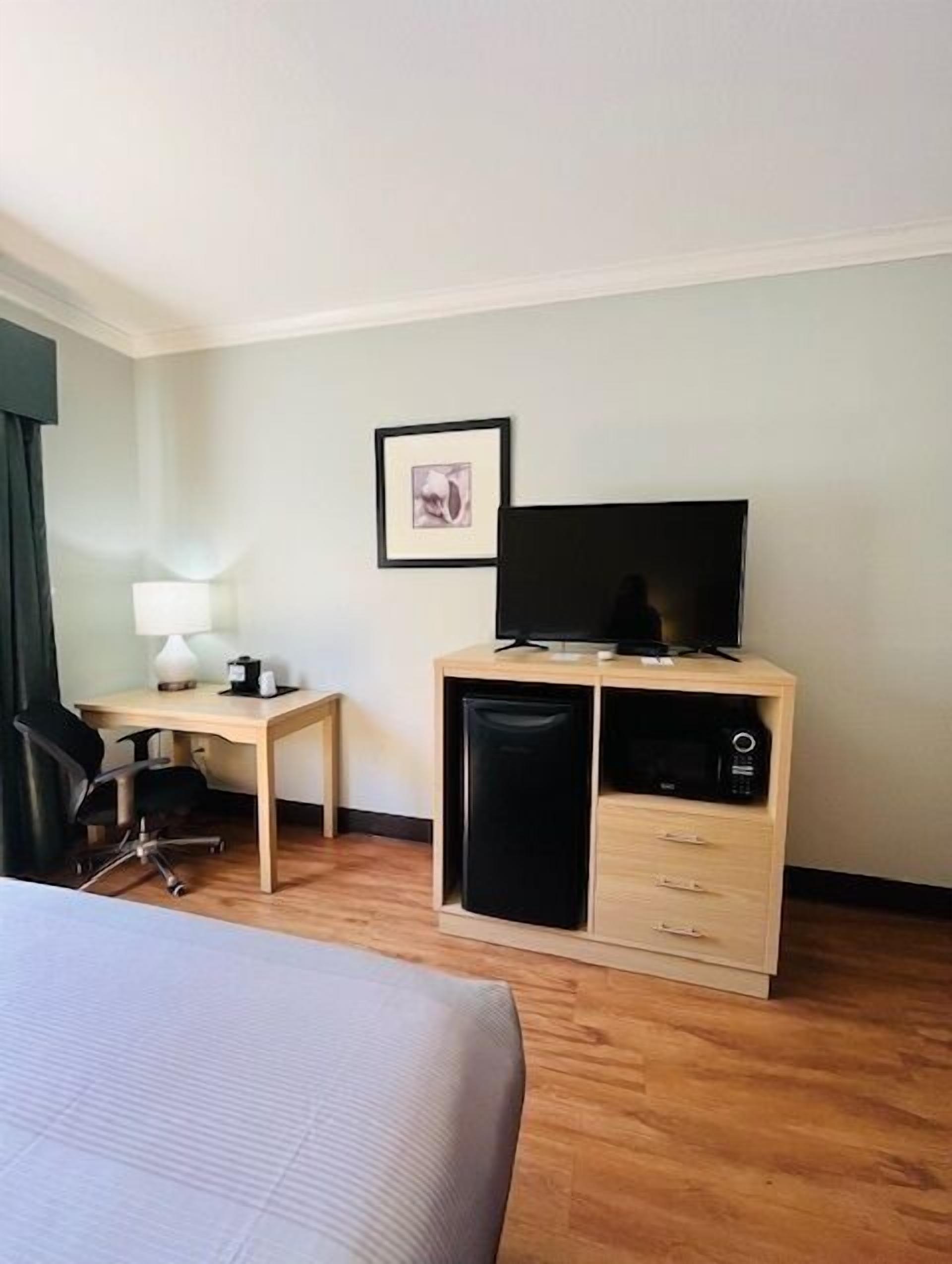 Une chambre d’hôtel équipée d’un lit, d’un bureau, d’une chaise, d’une télévision et d’un mini-bar.