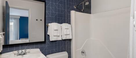 A bathroom with a white sink, a toilet, a shower with a glass door, and a mirror above the sink.
