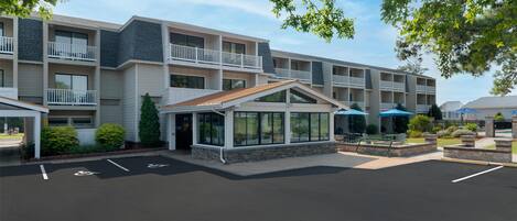 A multi-story hotel with a central courtyard, outdoor seating, and a covered entrance.