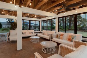 A spacious indoor area with a white sofa set, round tables, and large windows offering views of the outdoors. - Spark by Hilton Chincoteague Island (Chincoteague)