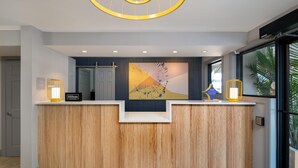 A reception desk with a wooden finish, a large abstract artwork above it, and a 'Hilton Honors' sign. - Spark by Hilton Chincoteague Island (Chincoteague)