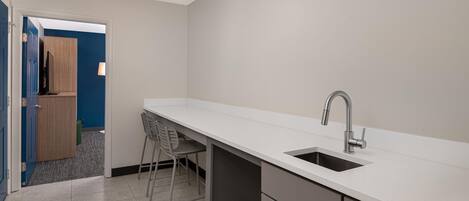 A kitchen with a white countertop, a sink, and a chair.