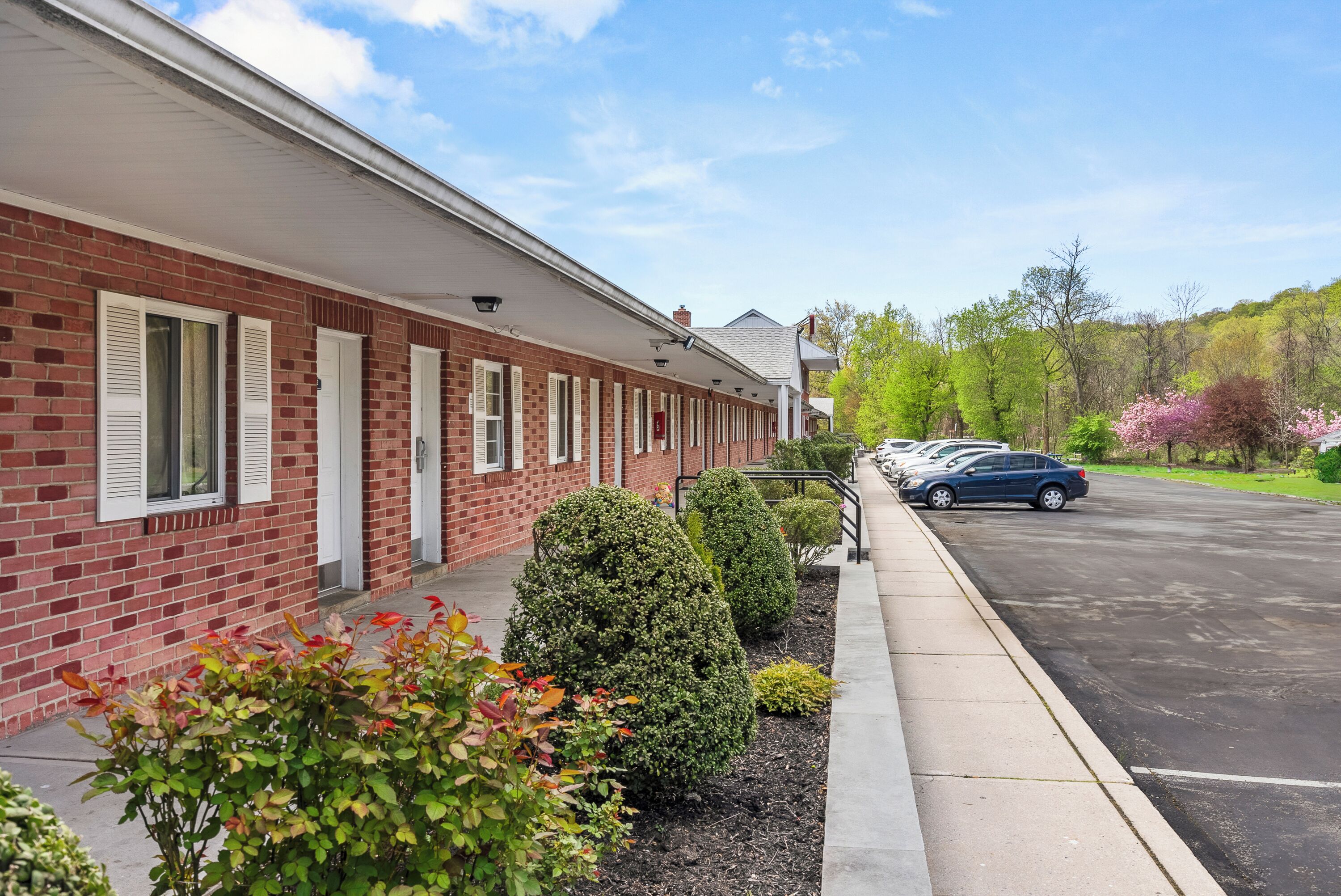 A brick building with white shutters and a parking lot.