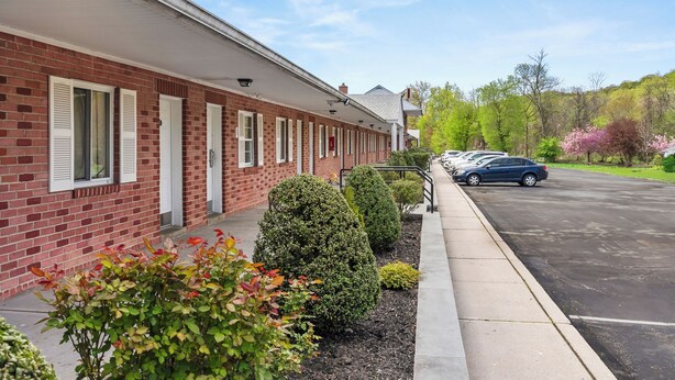 A brick building with white shutters and a parking lot. - Ardsley Acres Hotel Westchester (Ardsley)
