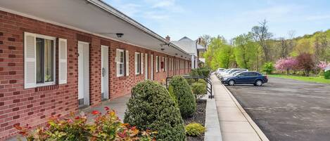 A brick building with white shutters and a parking lot.