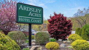 A sign for Ardsley Acres Hotel Court with a landscaped garden in the background. - Ardsley Acres Hotel Westchester (Ardsley)