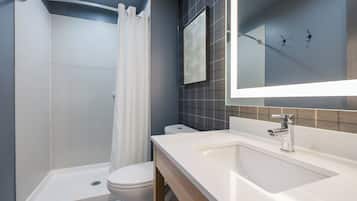 A modern bathroom with a shower, toilet, and sink.