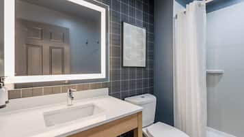 A modern bathroom with a white sink, a mirror, a toilet, and a shower curtain.