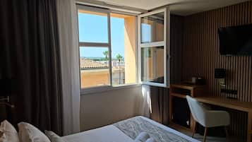 Una habitación de hotel con cama, escritorio, silla y televisor.