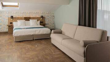 A bedroom with a bed, a sofa, a nightstand, and a wall-mounted lamp.
