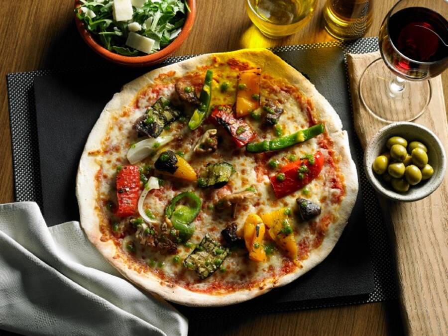 A pizza with various vegetables on a wooden table.