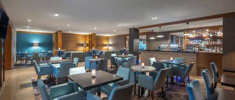 A hotel lobby with multiple seating areas, a bar, and a reception desk.