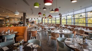Un restaurante con varias mesas, sillas e iluminación colgante.