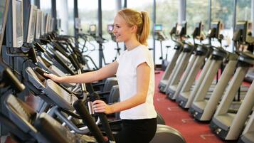 Un gimnasio con varias cintas de correr dispuestas en filas.