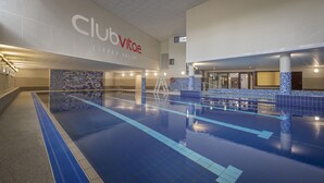 Una piscina interior con carriles claramente delimitados, un puesto de socorrista y un letrero que dice "Club Vitas".