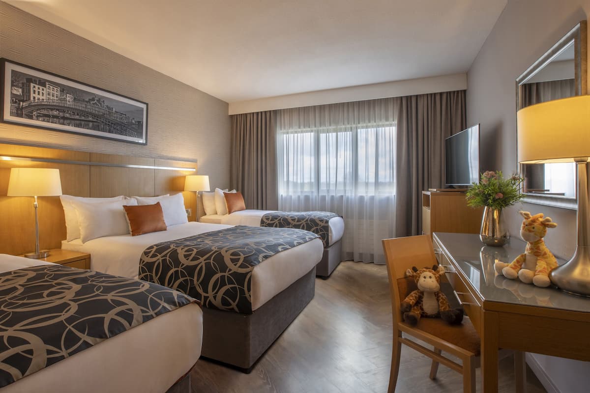 A hotel room with two beds, a desk, a chair, a television, and a framed picture on the wall.