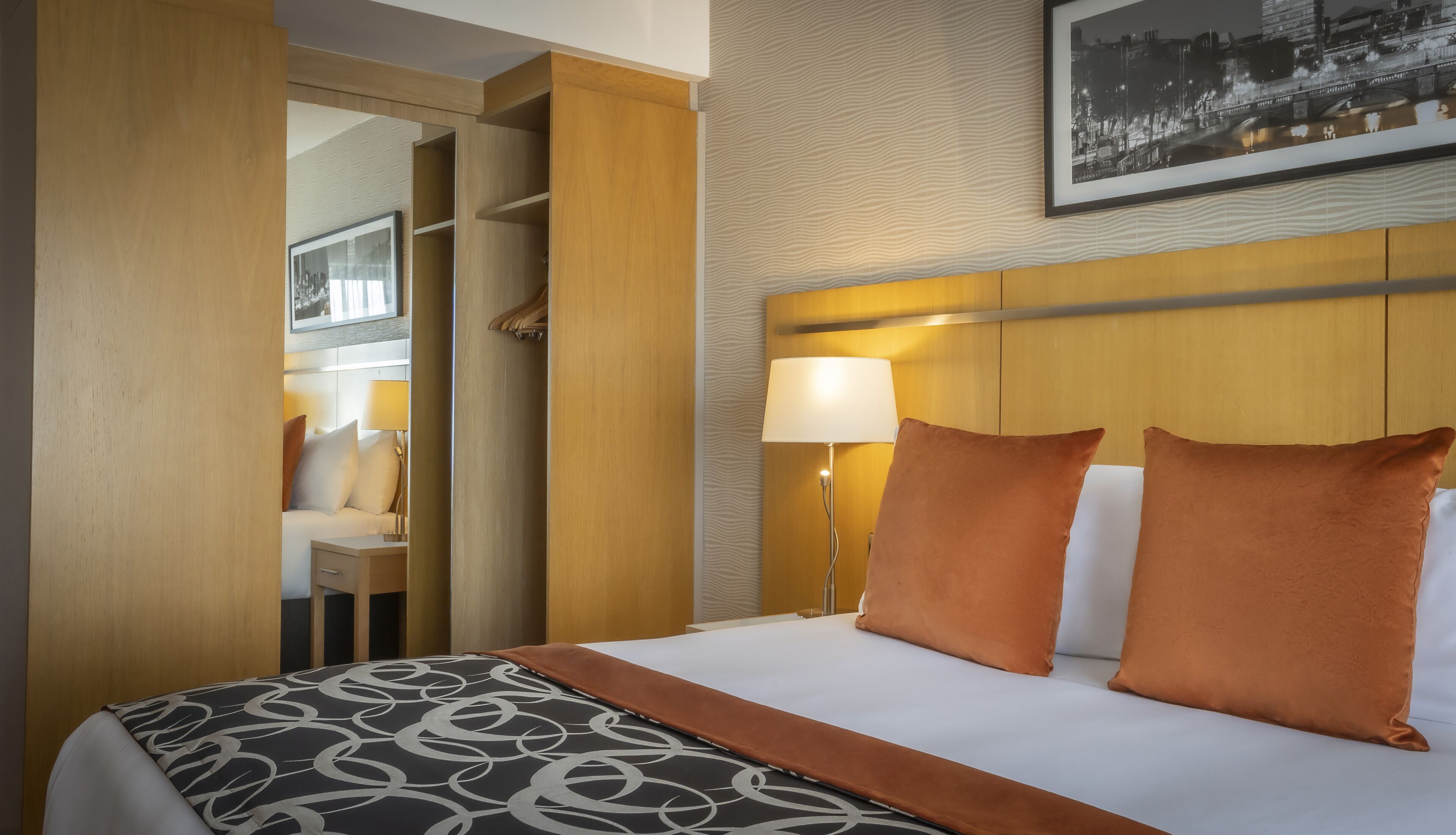 A hotel room with a bed, a nightstand, a lamp, and a wardrobe.