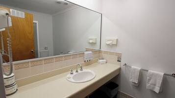 Une salle de bain équipée d’un lavabo, d’un miroir, d’un porte-serviettes et d’un sèche-mains.